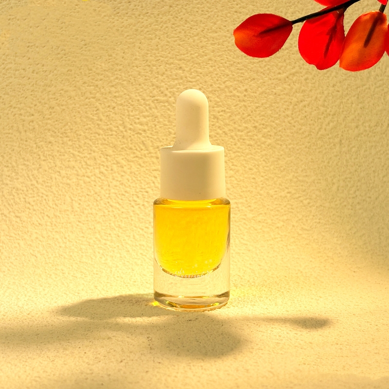 Små eteriske oljeflasker av glass med dråper av metall eller tre